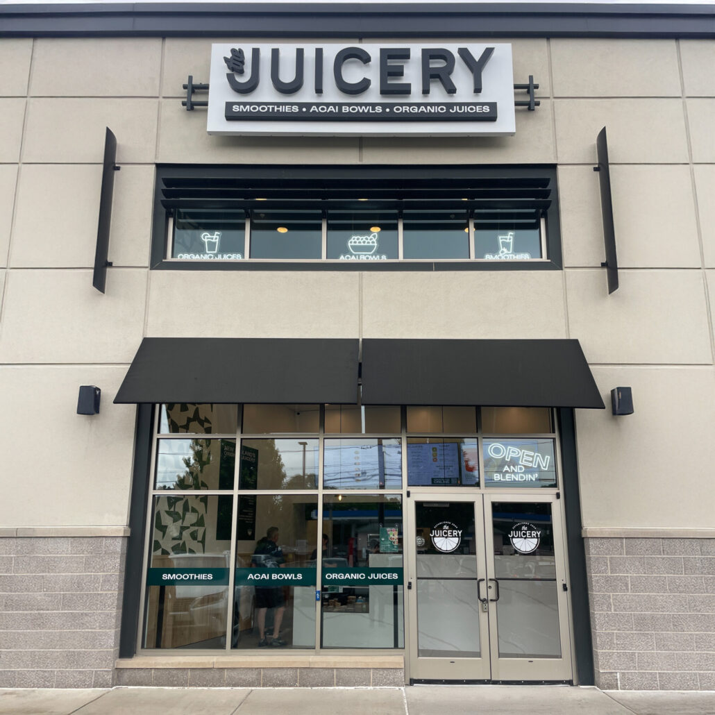 Exterior of The Juicery’s Waltham location with contemporary signage, glass storefront, and awnings.