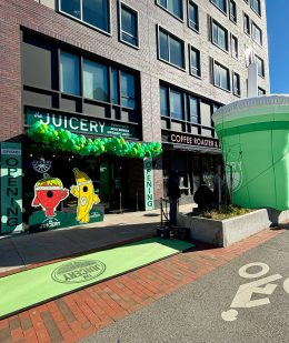 Exterior of The Juicery’s Cambridge location decorated with green balloons and window graphics during the grand opening.