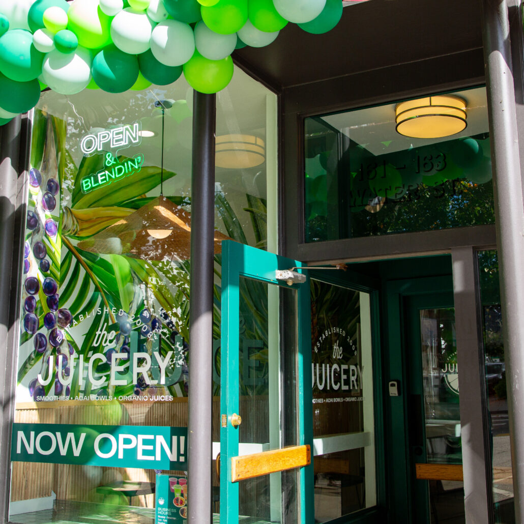 Entrance of The Juicery decorated with green and white balloons for a grand opening.