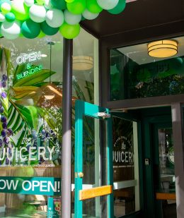 Entrance of The Juicery decorated with green and white balloons for a grand opening.